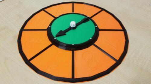 A photo of a brightly coloured game spinner featuring a tray around the outside which can hold game pieces.