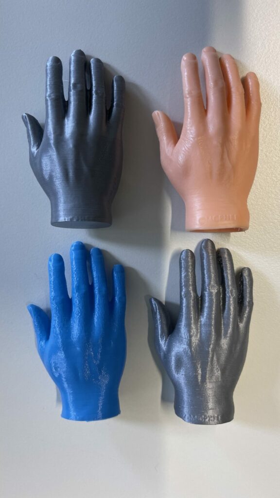 Photo of a hand made of rubber together with 3 3d printed copies.