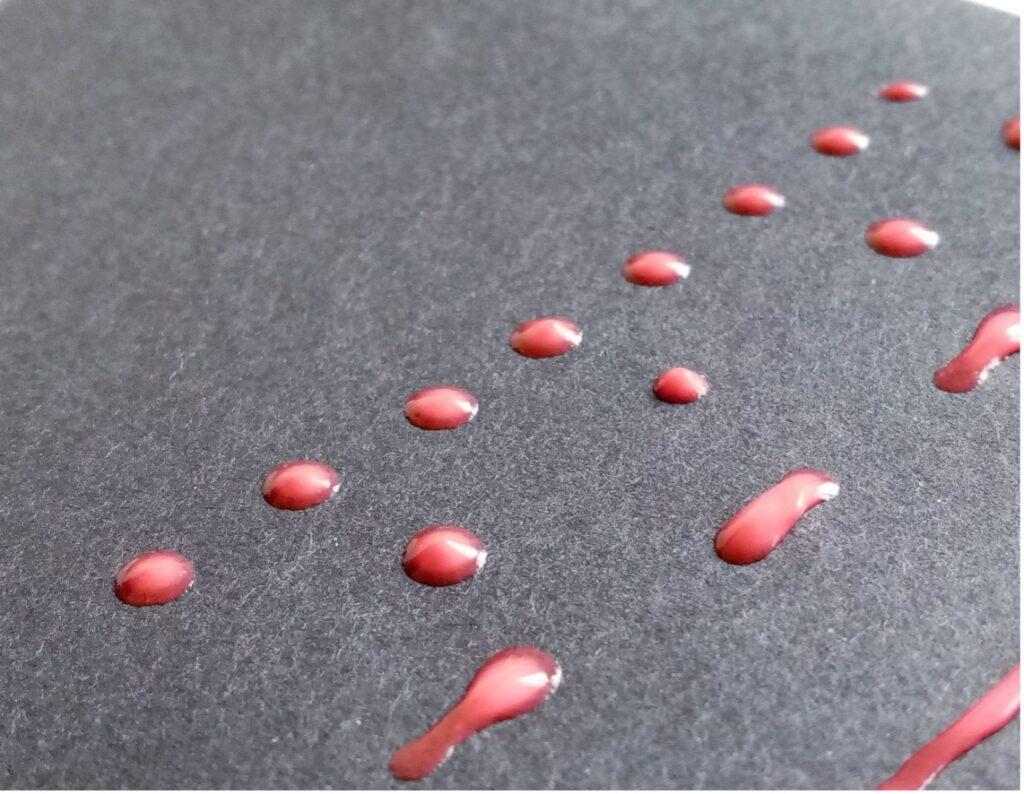 Close up image of dried red glue, spread in dotted and dashed line