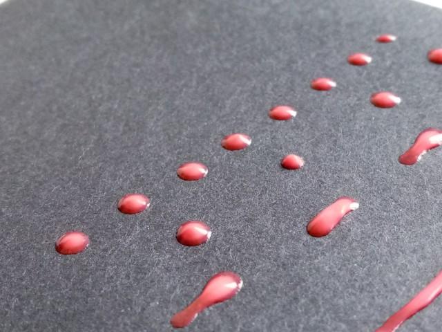 Close up image of dried red glue, spread in dotted and dashed lines.