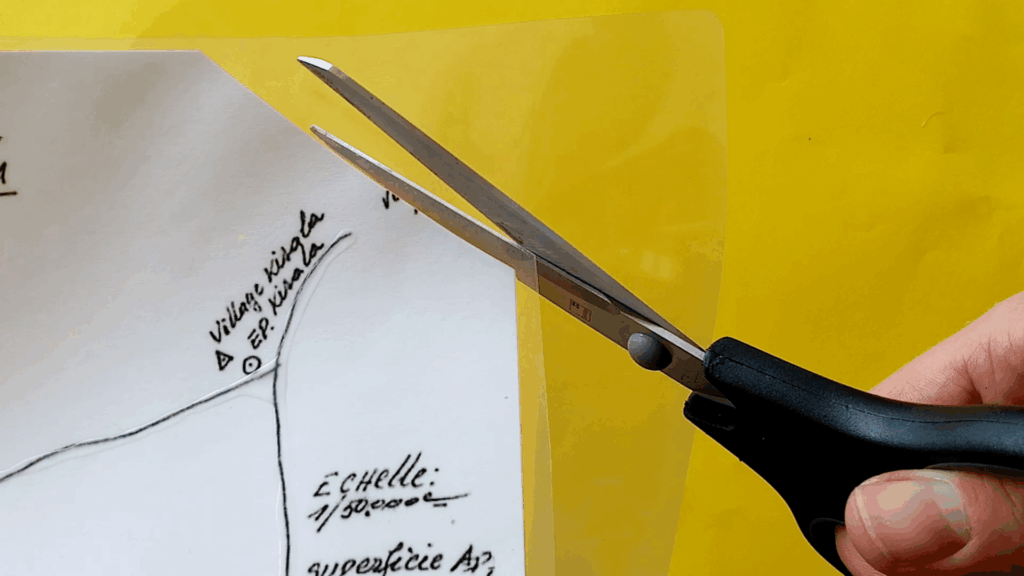 The upper right corner of the map is shown. A scissor is used to cut off the excess lamination, following the previous 45 degree cut.
