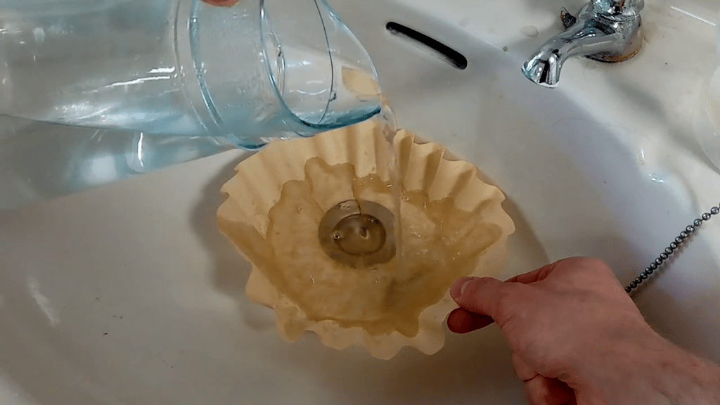 A coffee filter is placed into a sink. The water which was in contact with the material is gradually poured into the filter.