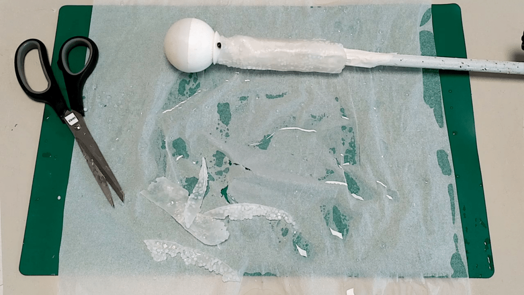 The material is wrapped around the cable tie enforced popsicle sticks. The transparency of the material decreased, it’s starting to solidify.