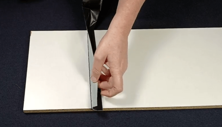 Folding the tape width double, non-sticking sides against each other.