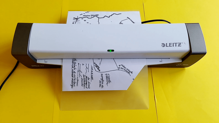 The upper right corner of the map is shown. A scissor is used to cut off the excess lamination, following the previous 45 degree cut.